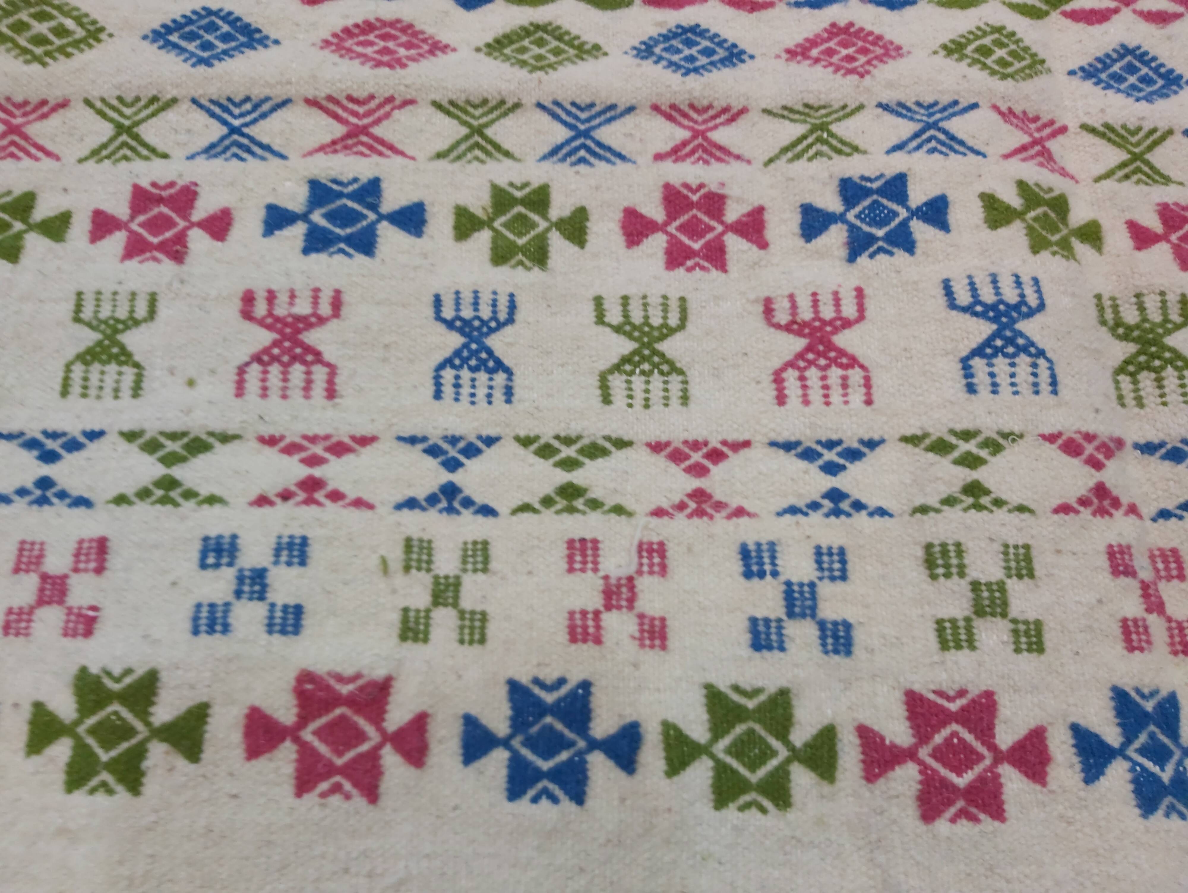 White carpet with Berber motifs pink green and blue