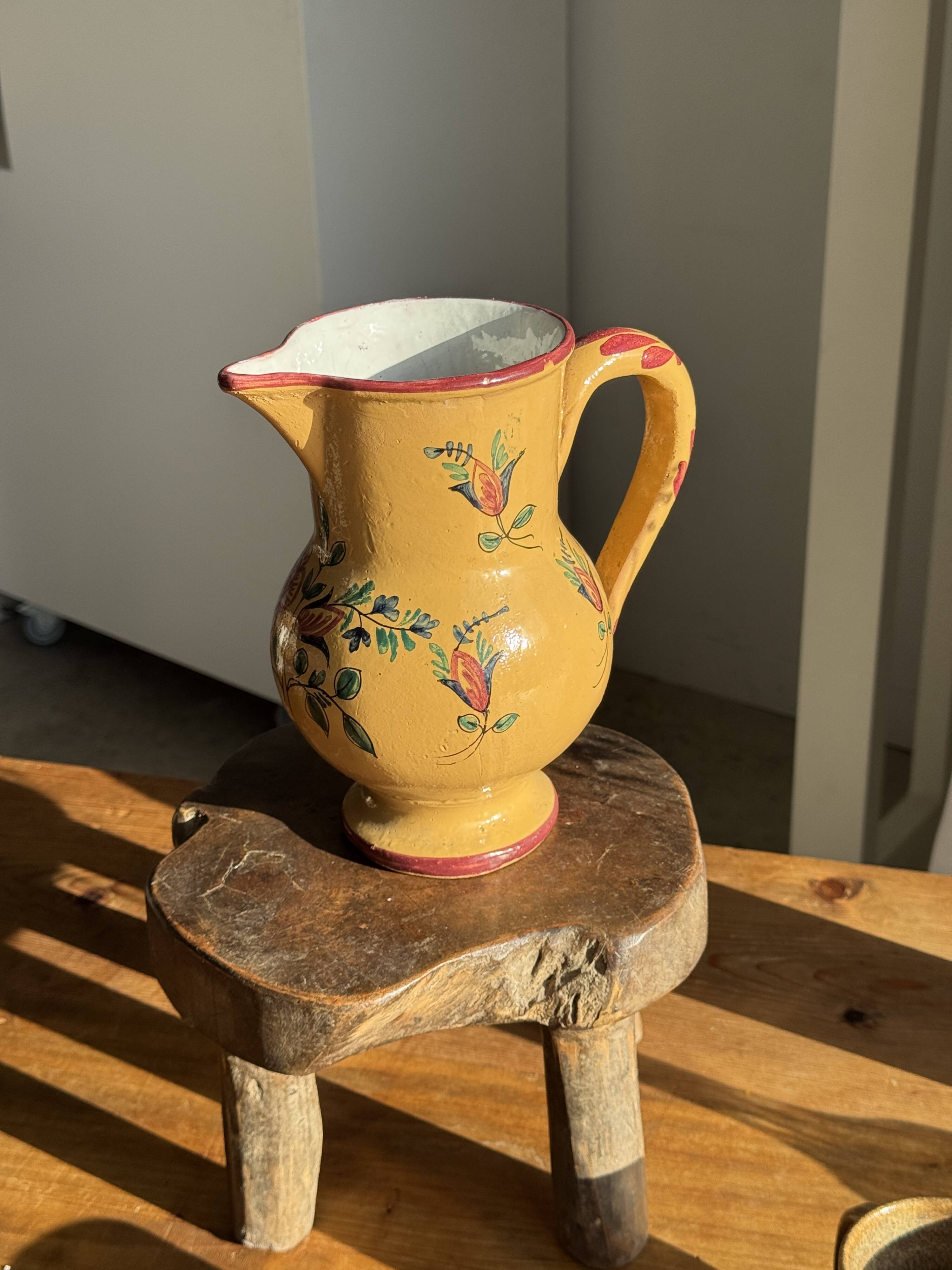Large antique handmade ochre yellow jug with a pink flower pattern.