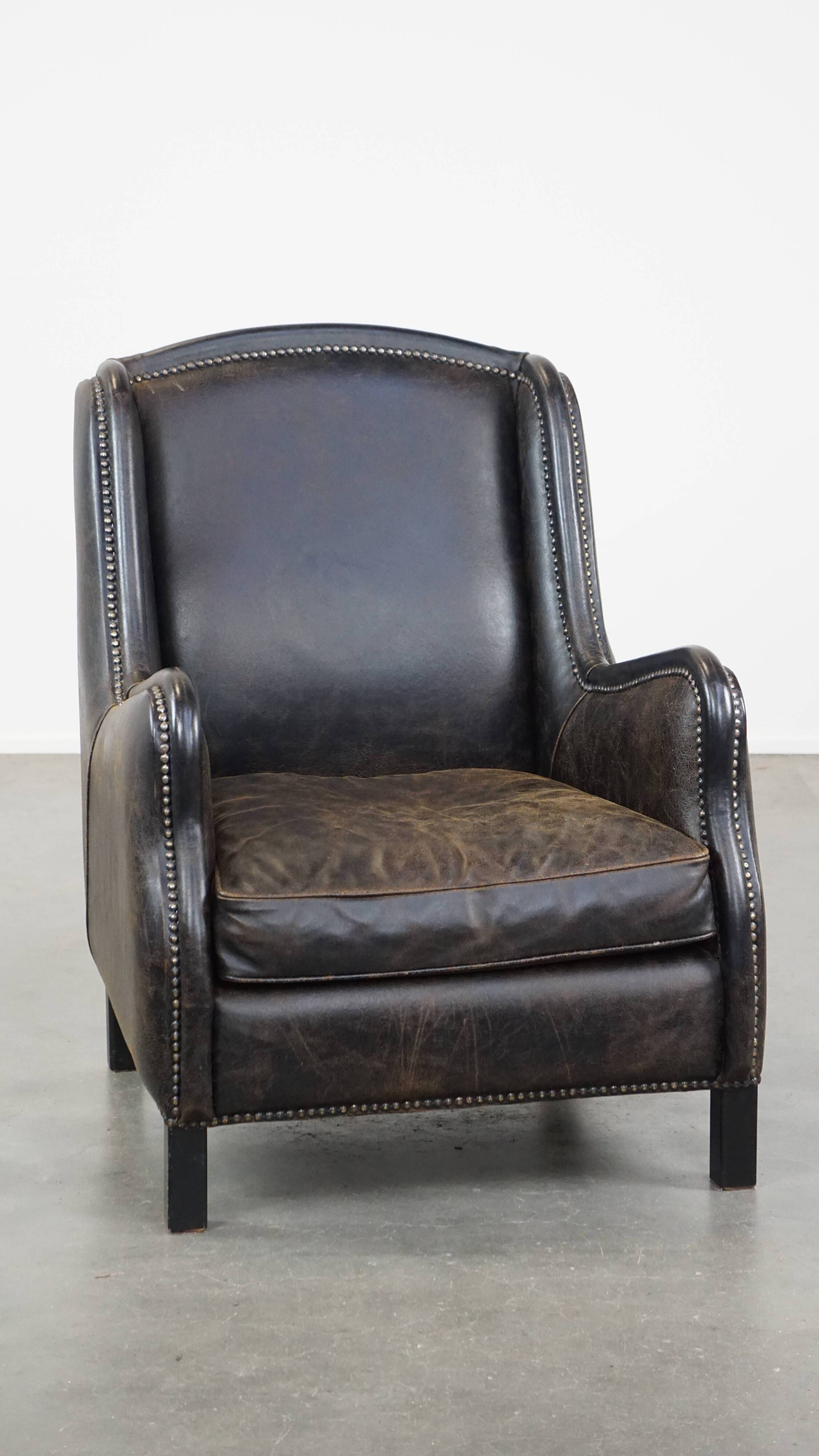 Black cow leather armchair in industrial style finished with decorative nails