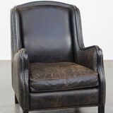 Black cow leather armchair in industrial style finished with decorative nails