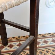 Vintage rustic stool in wood with a straw seat.
