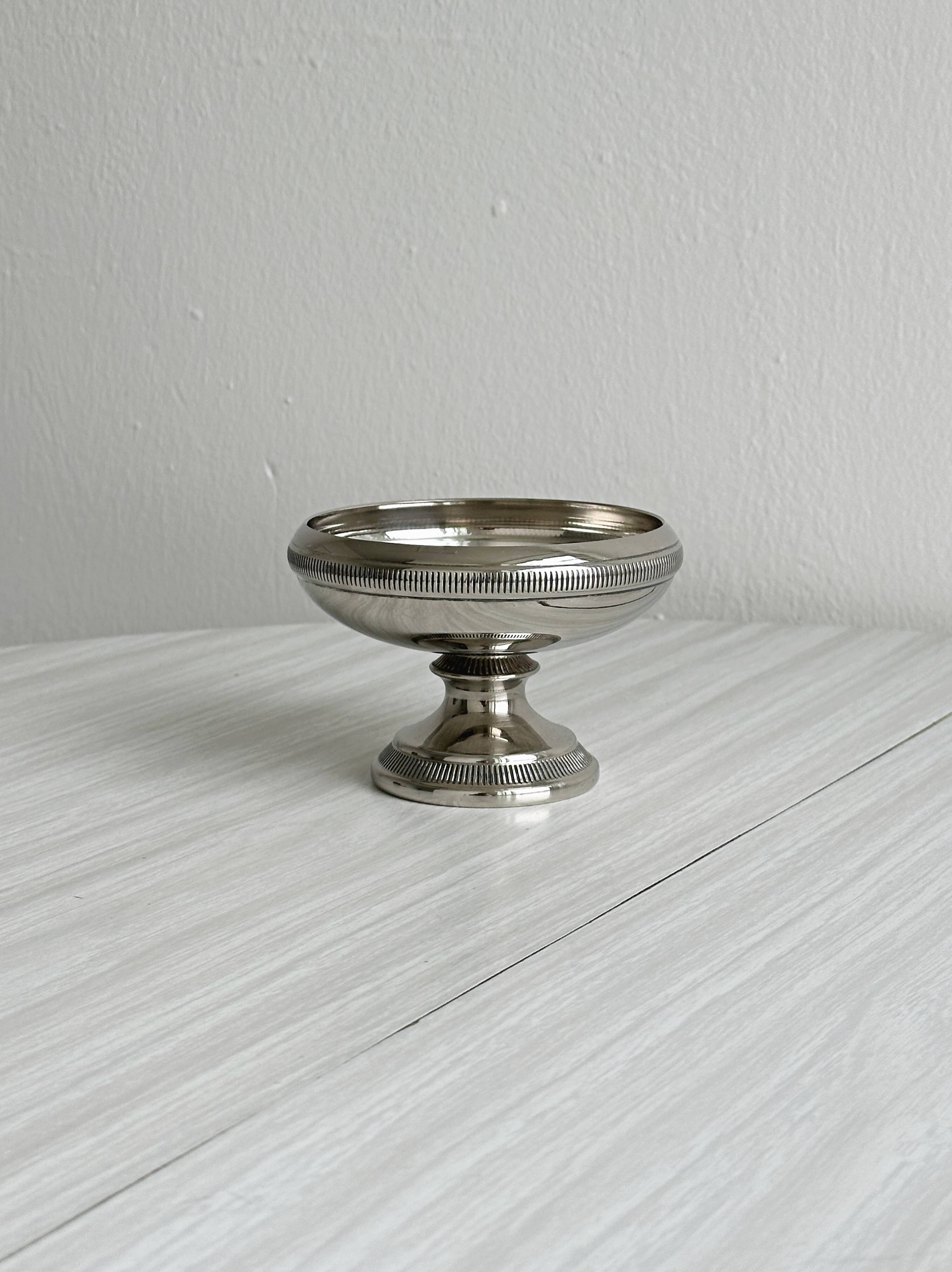 Small silver-plated metal bowl on a stand.
