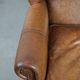 Fauteuil à oreilles de style anglais couleur cognac en cuir de vache.
