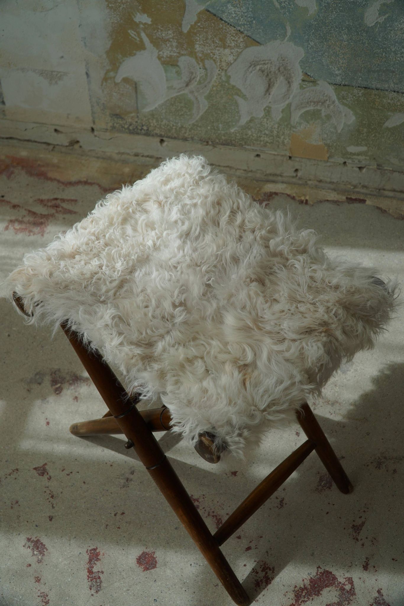 Folding stool, reupholstered in long-haired sheepskin, mid-century modern style, 1950s.