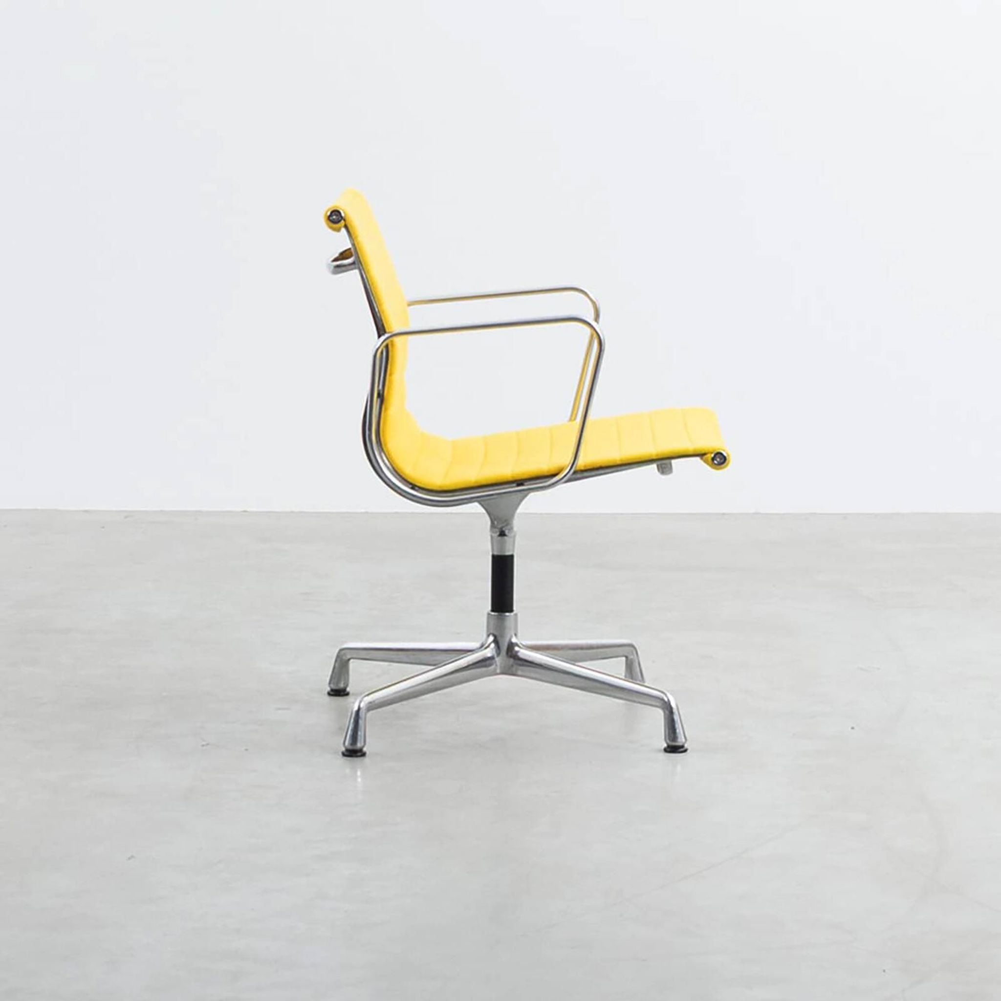 Fauteuil Aluminum Group EA107 de Charles et Ray Eames en tissu jaune.