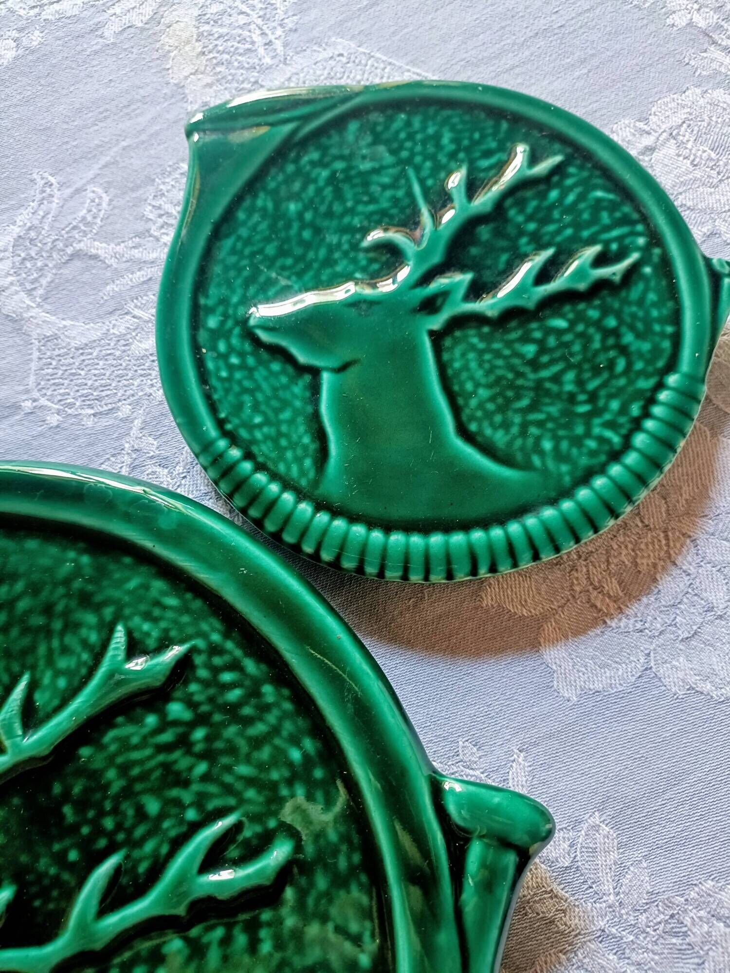 A trivet and two bottle holders in green Vallauris majolica.