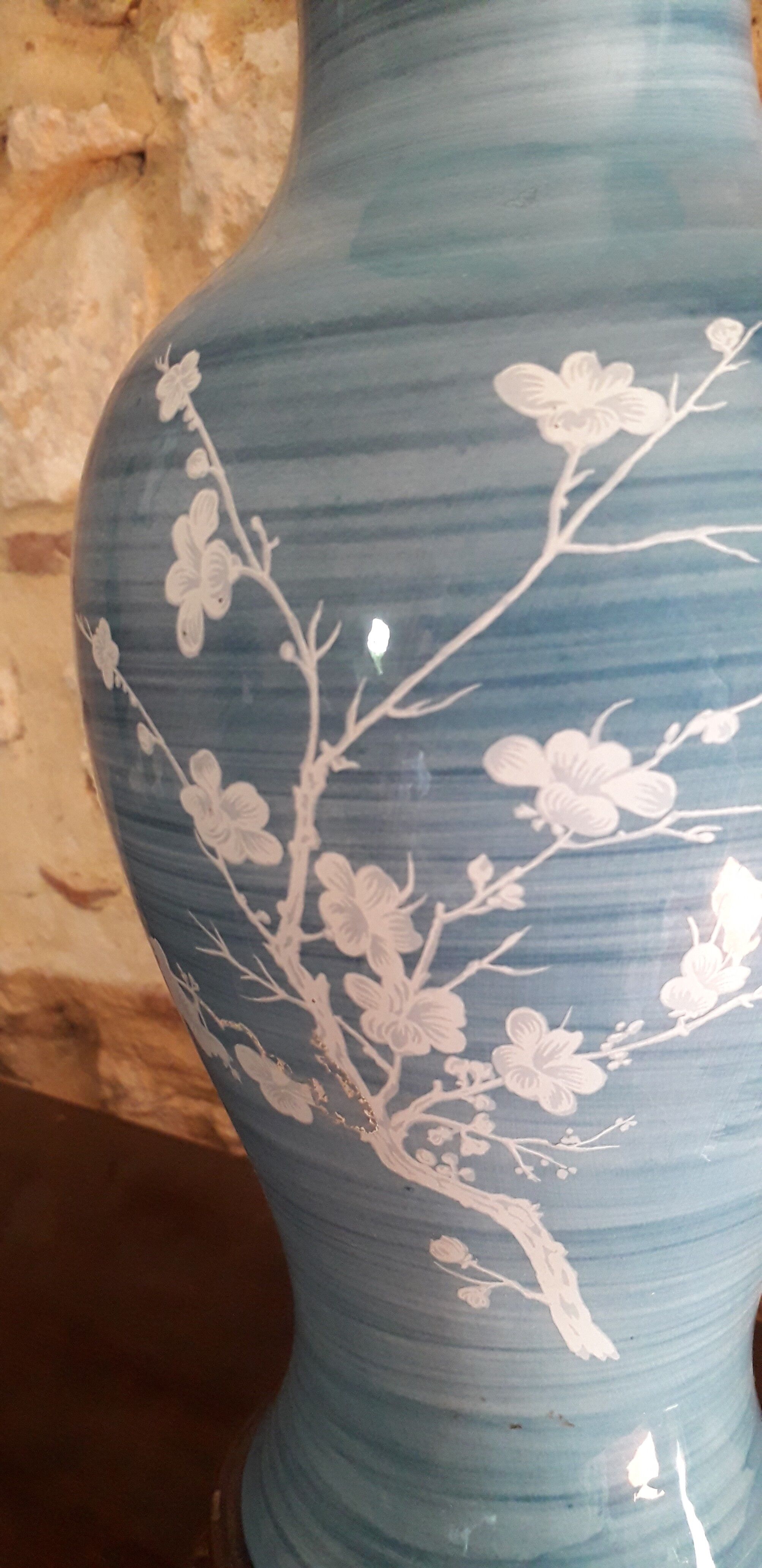 Large blue porcelain lamp with white flowers (cherry blossoms) on wooden stand.