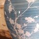Large blue porcelain lamp with white flowers (cherry blossoms) on wooden stand.