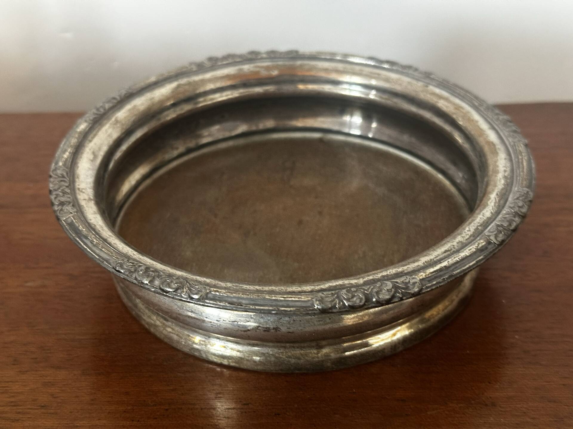 Antique silver-plated bottle coaster with floral decoration.