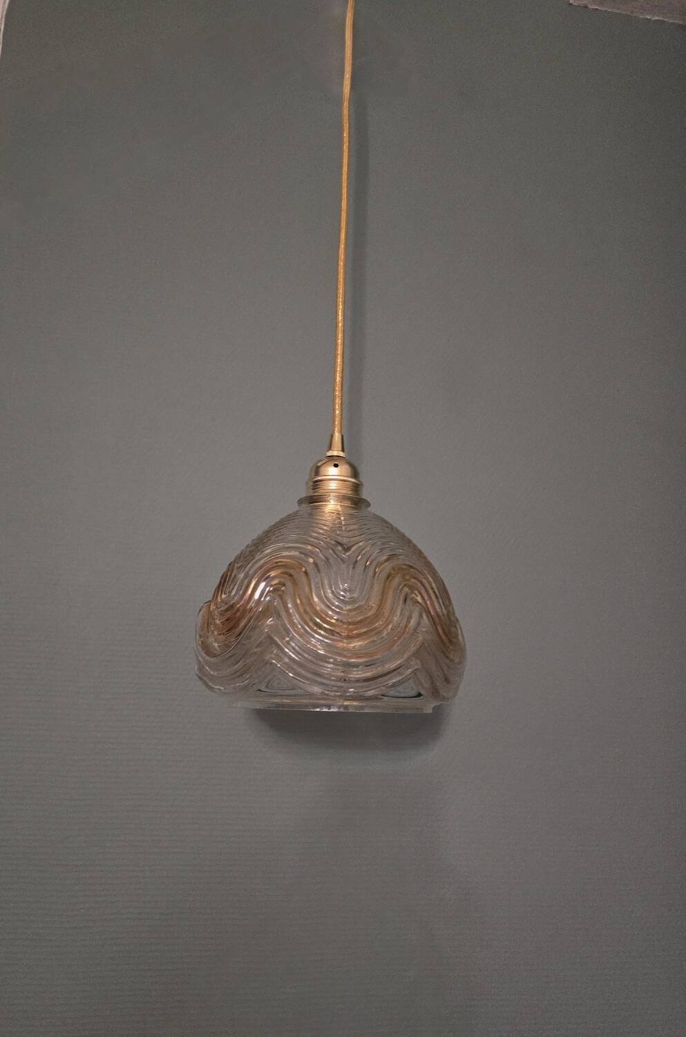 Suspension with amber moulded glass globe featuring wavy patterns.
