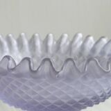 Purple glass pedestal bowl with wavy border and relief pattern.