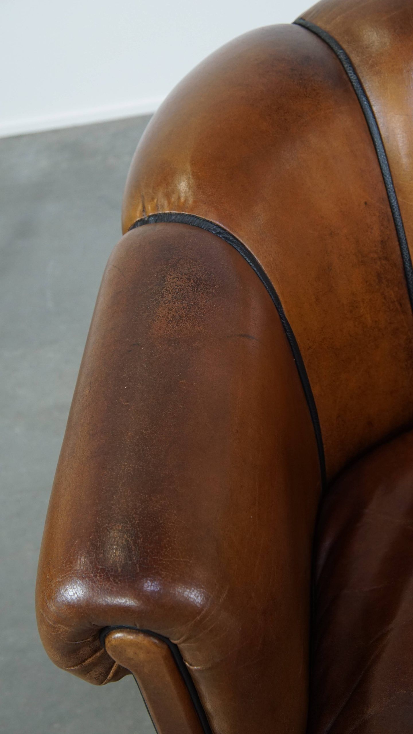 Unique vintage cognac-coloured leather club armchair with black piping
