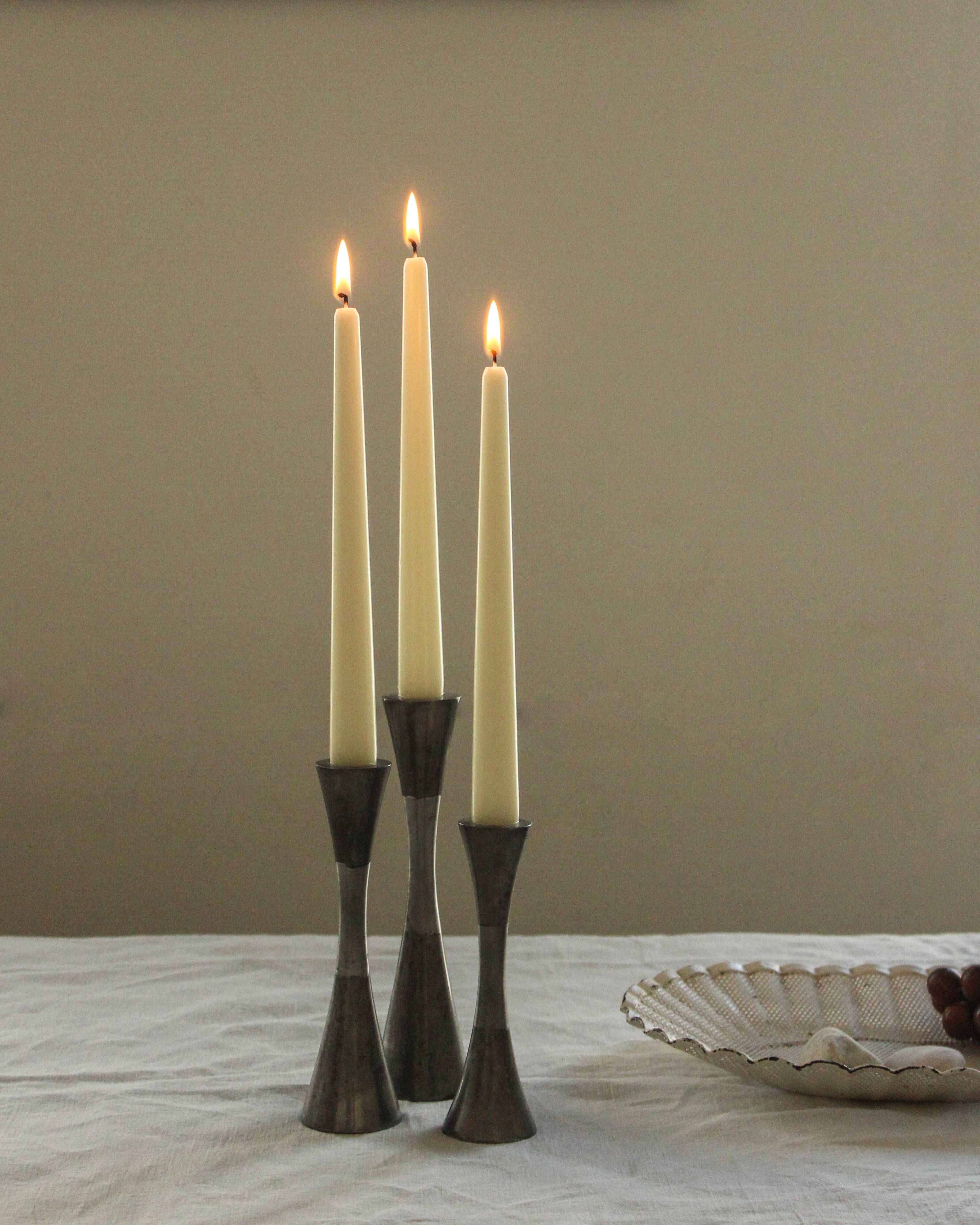 Set of three diabolo-shaped candle holders made of cast steel.