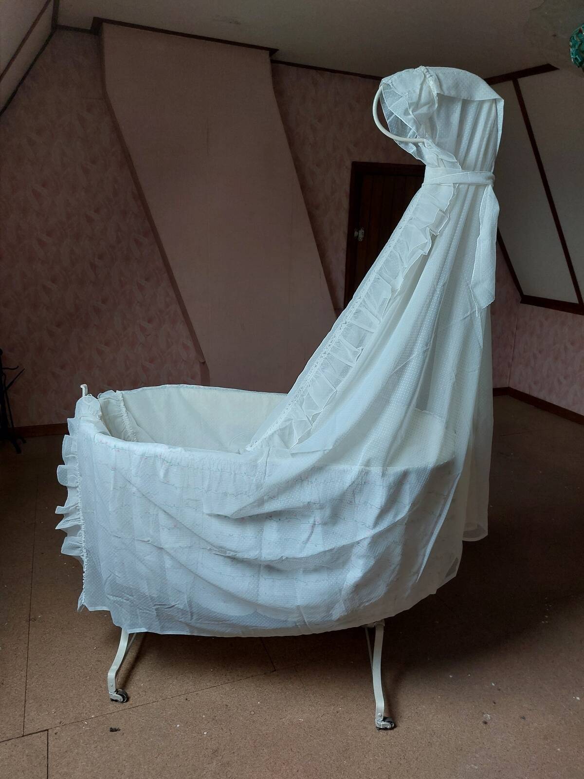 Wrought iron crib painted white from around 1920 with bedding.