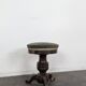 Green velvet piano stool with a turned leg.