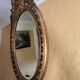 Antique oval mirror in gilded stucco with ornamentation
