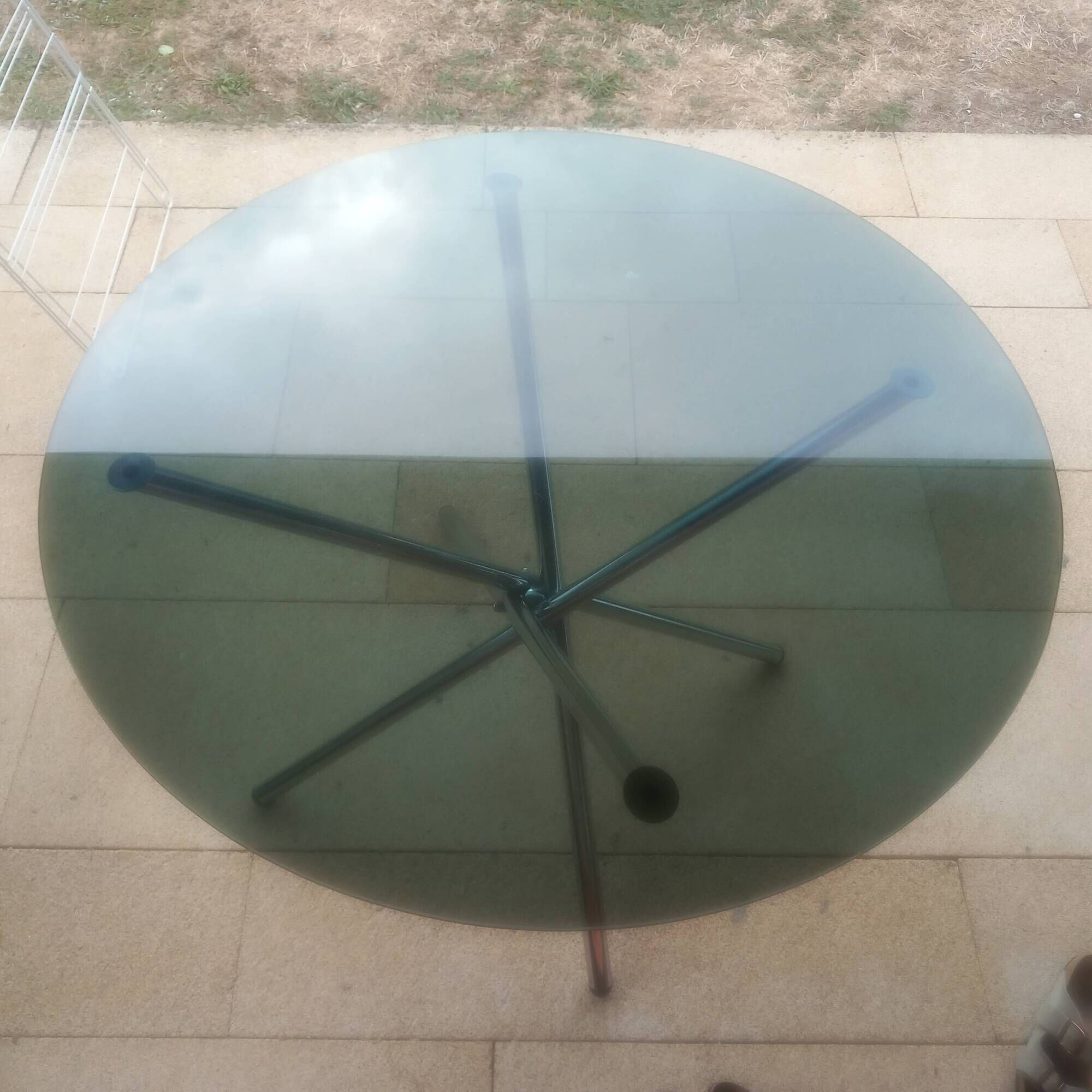 Round smoked glass table from the 70s. Foldable stainless steel legs.