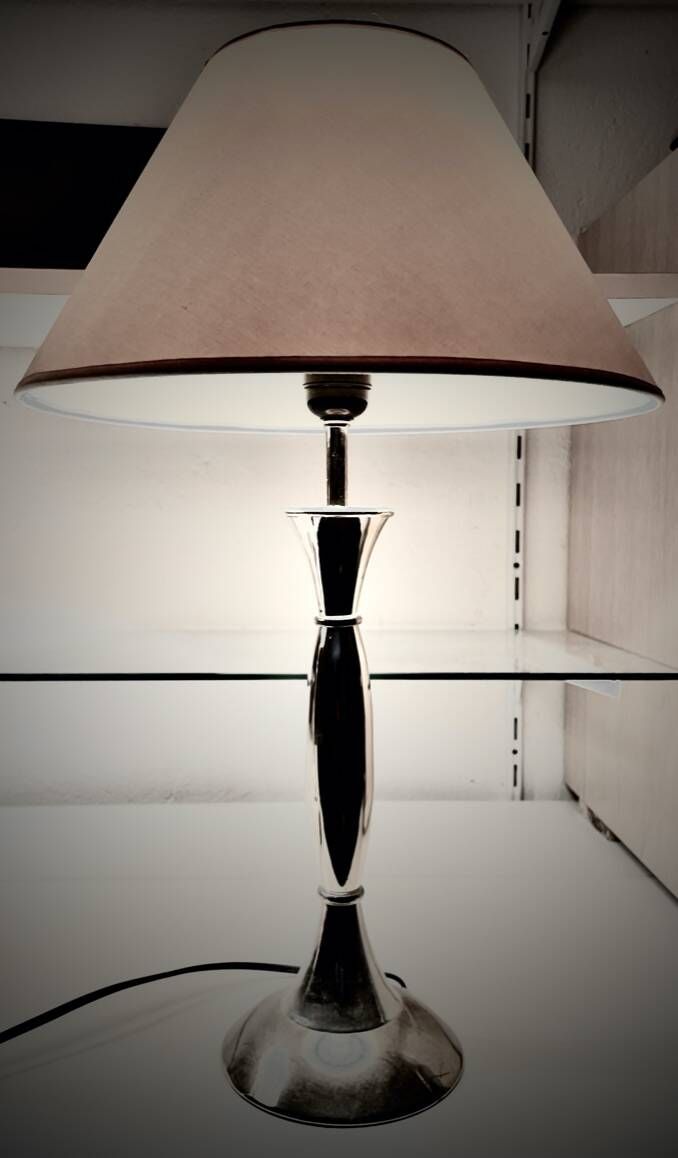 Contemporary table lamp in polished chrome with a conical fabric shade.