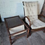 Relaxed armchair in bamboo and rattan with its small side table. Beige linen cushion.