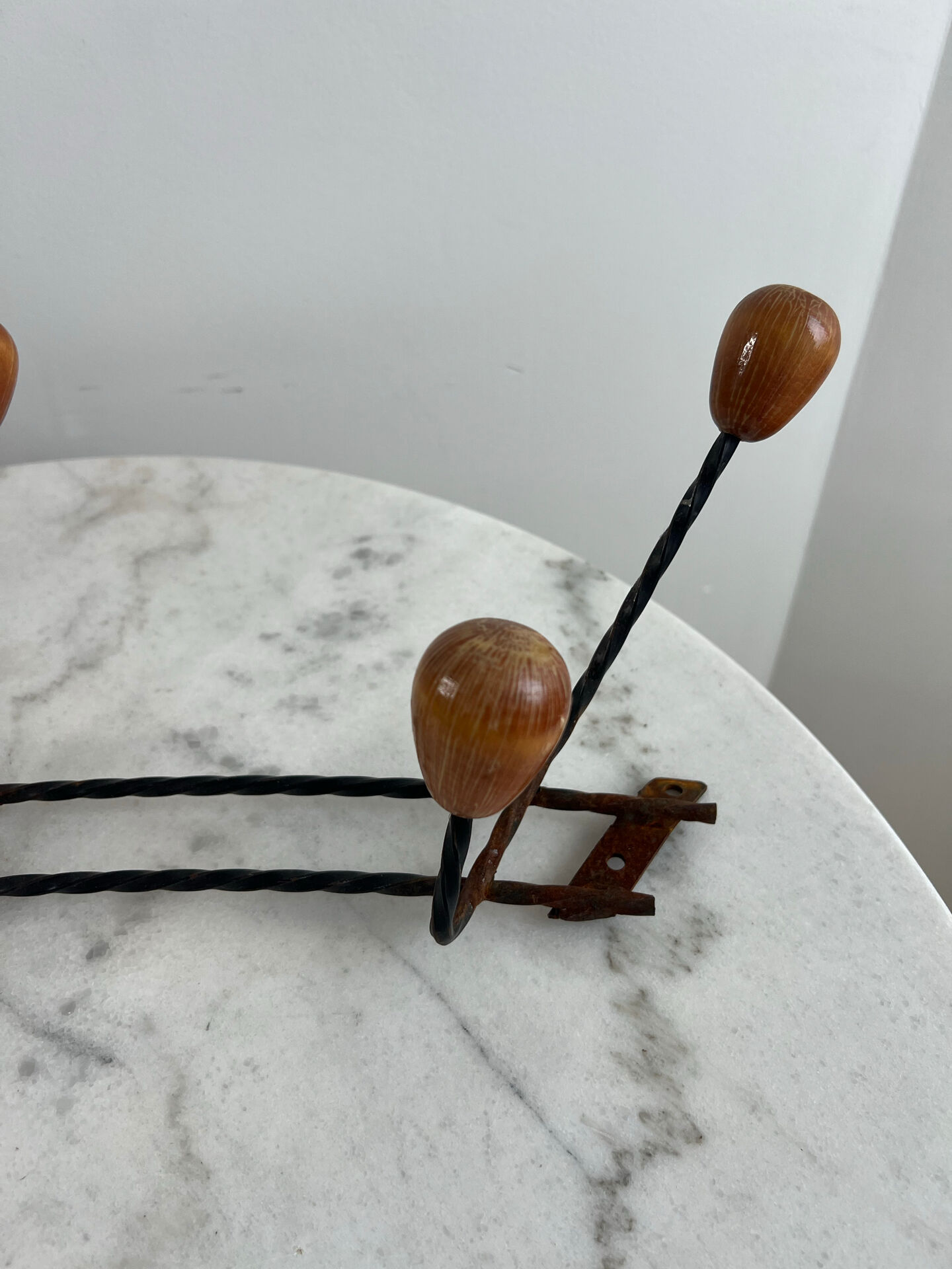 Wall-mounted coat rack in wrought iron with turned wooden knobs.