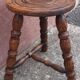 Low wooden tripod stool.