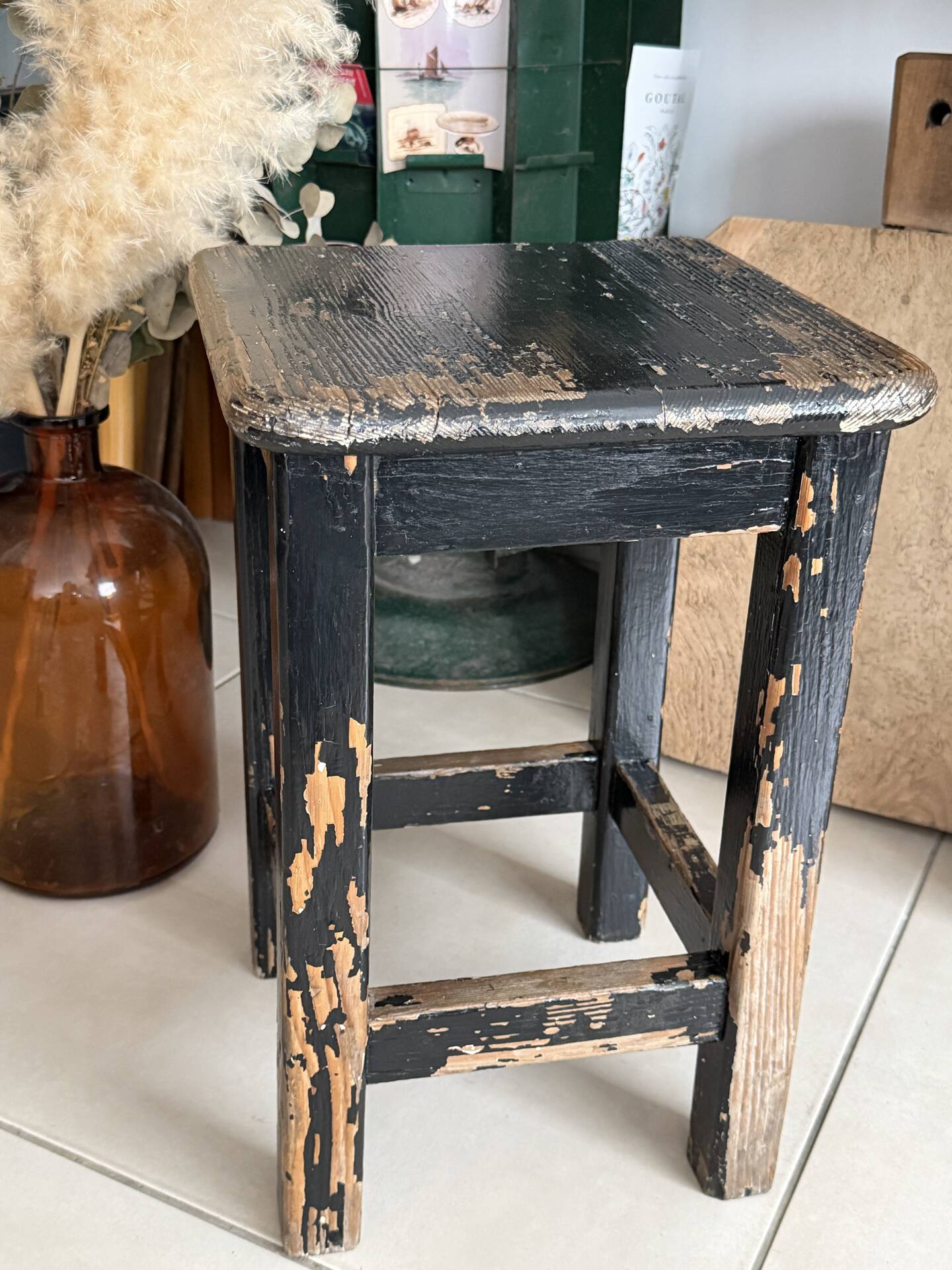 Solid wood stool with a worn black patina.