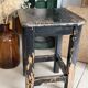 Solid wood stool with a worn black patina.