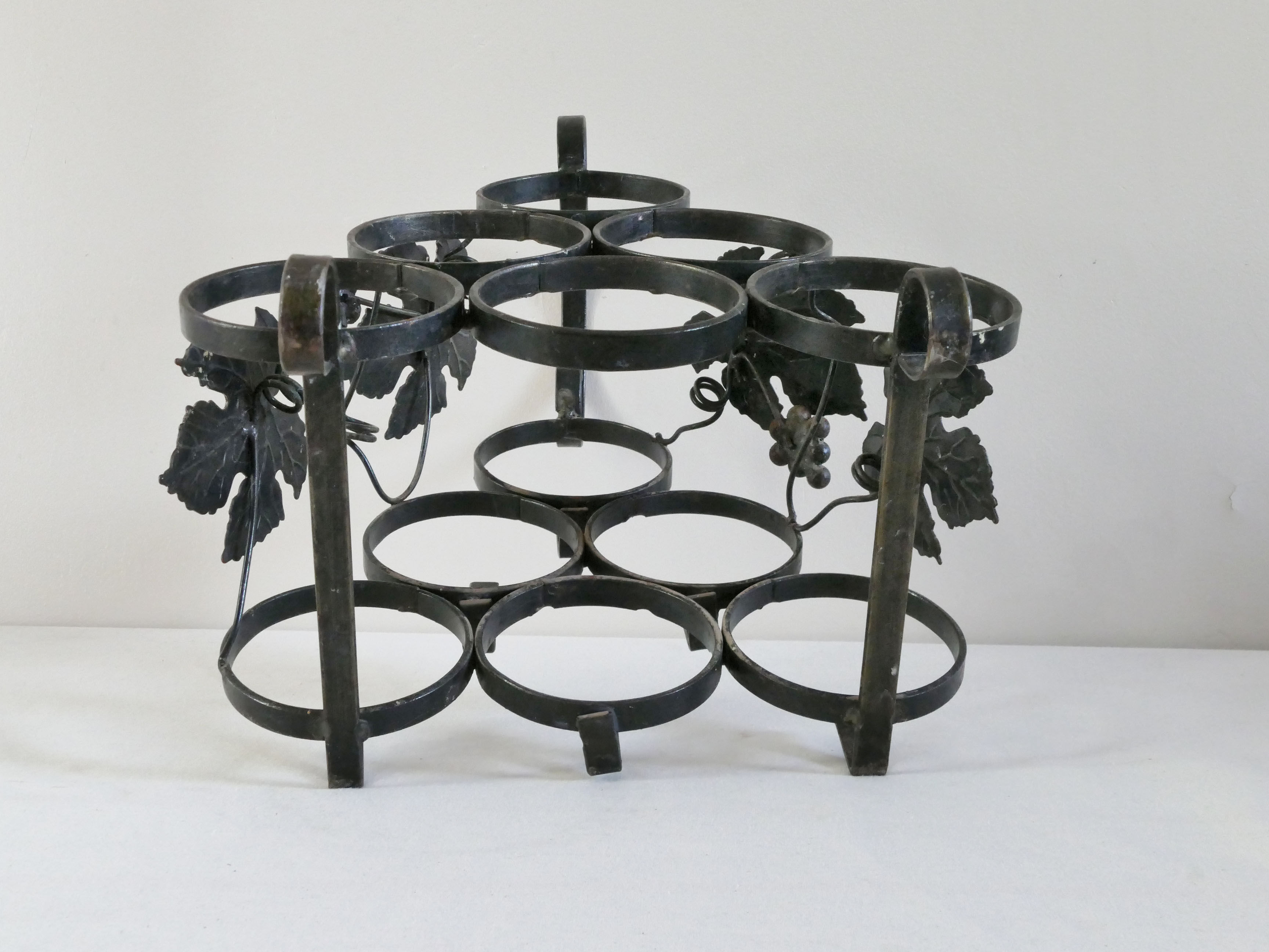 Vintage black wrought iron bottle holder decorated with vine leaves