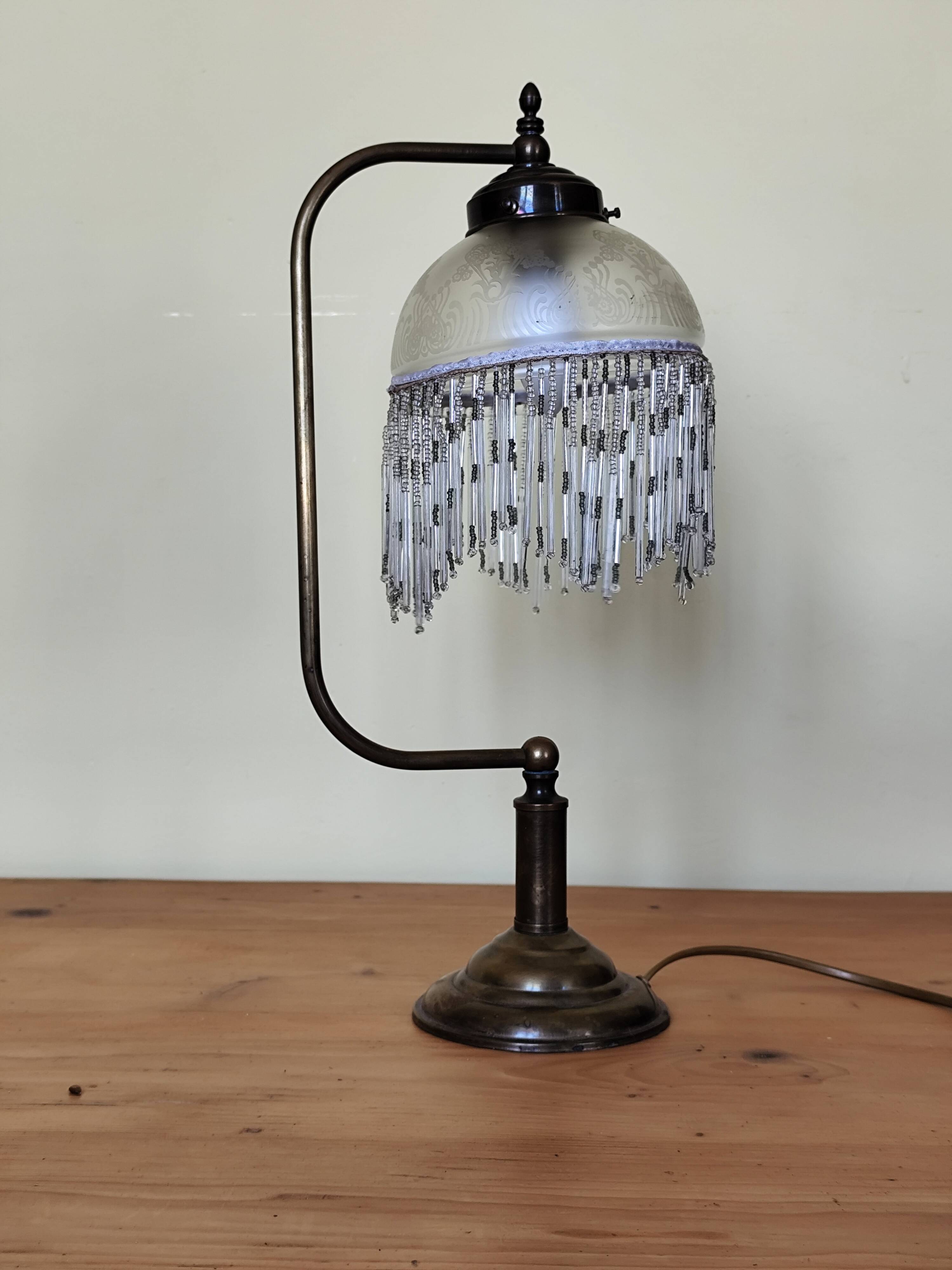 Retro brass lamp with a glass shade and bead fringes.
