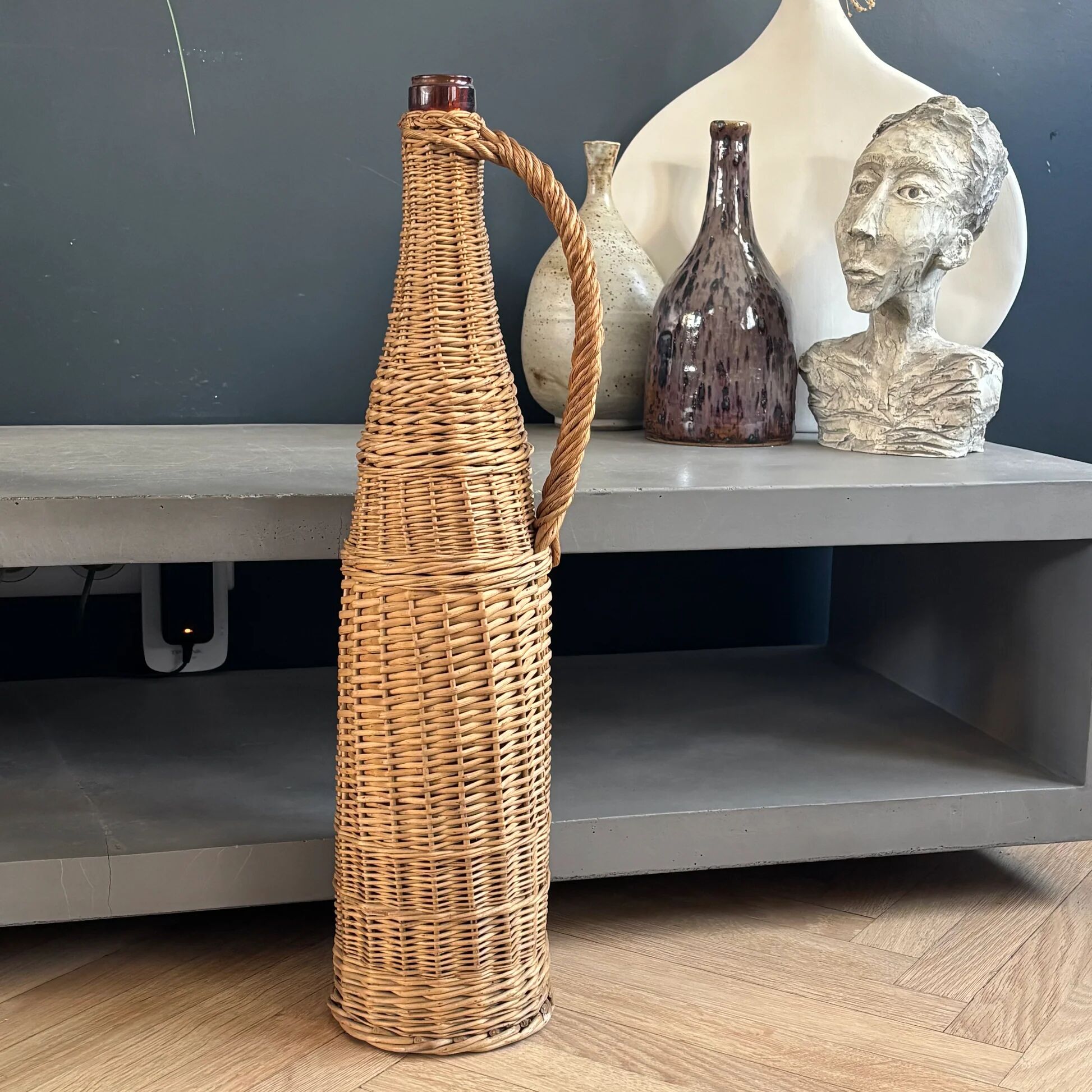 Amber glass bottle in its wicker handle basket.