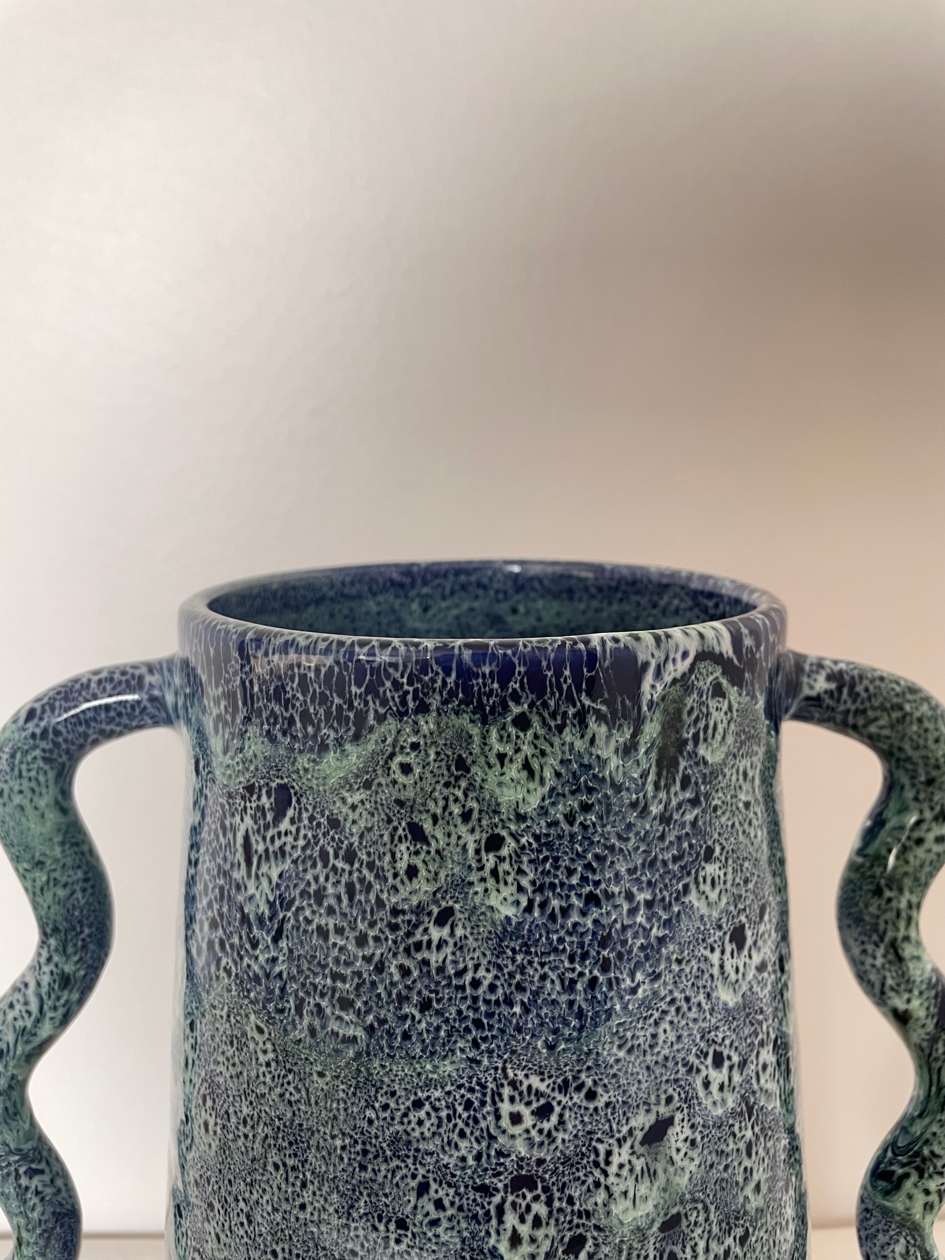 Blue-green ceramic vase with abstract wavy handles