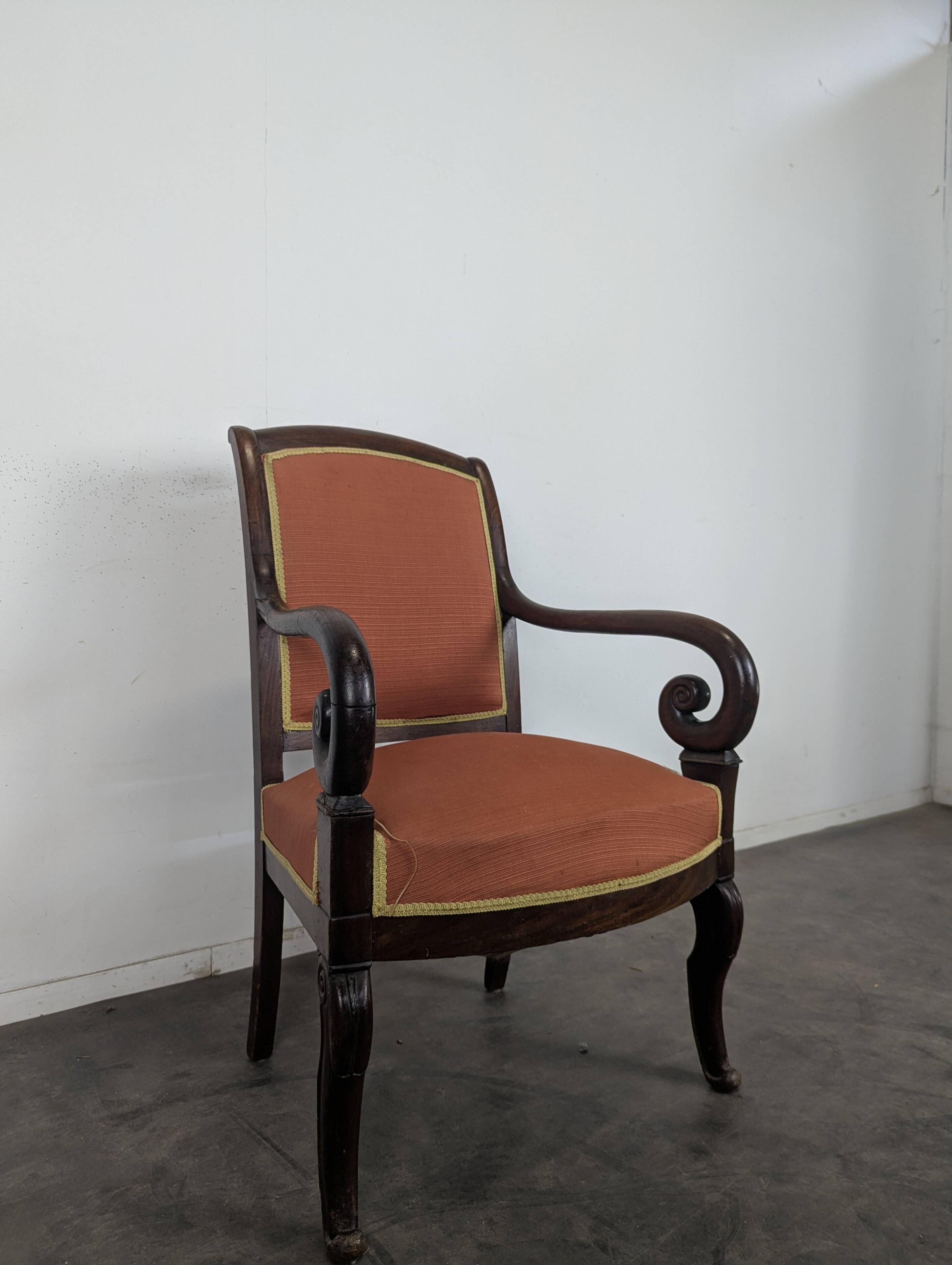 Restoration armchair in mahogany with cross arms and orange fabric.