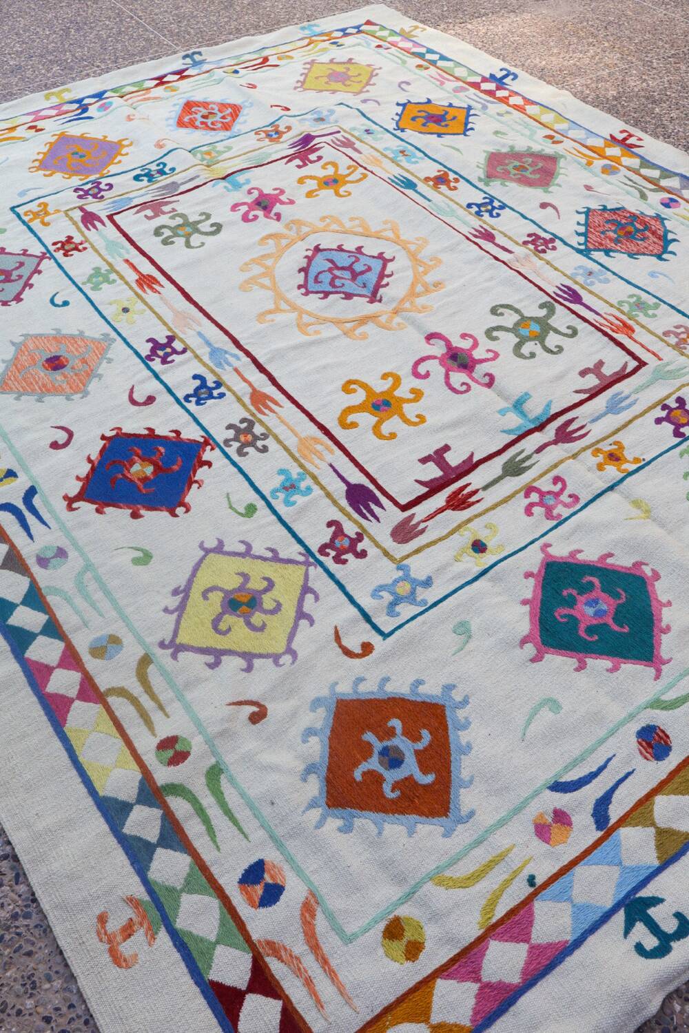 White suzani kilim rug with multi-colored embroidered patterns