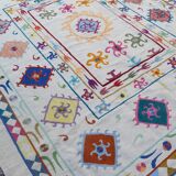 White suzani kilim rug with multi-colored embroidered patterns