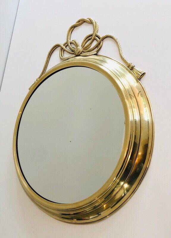 Large decorative oval mirror in brass adorned with a significant twisted bow.