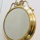 Large decorative oval mirror in brass adorned with a significant twisted bow.