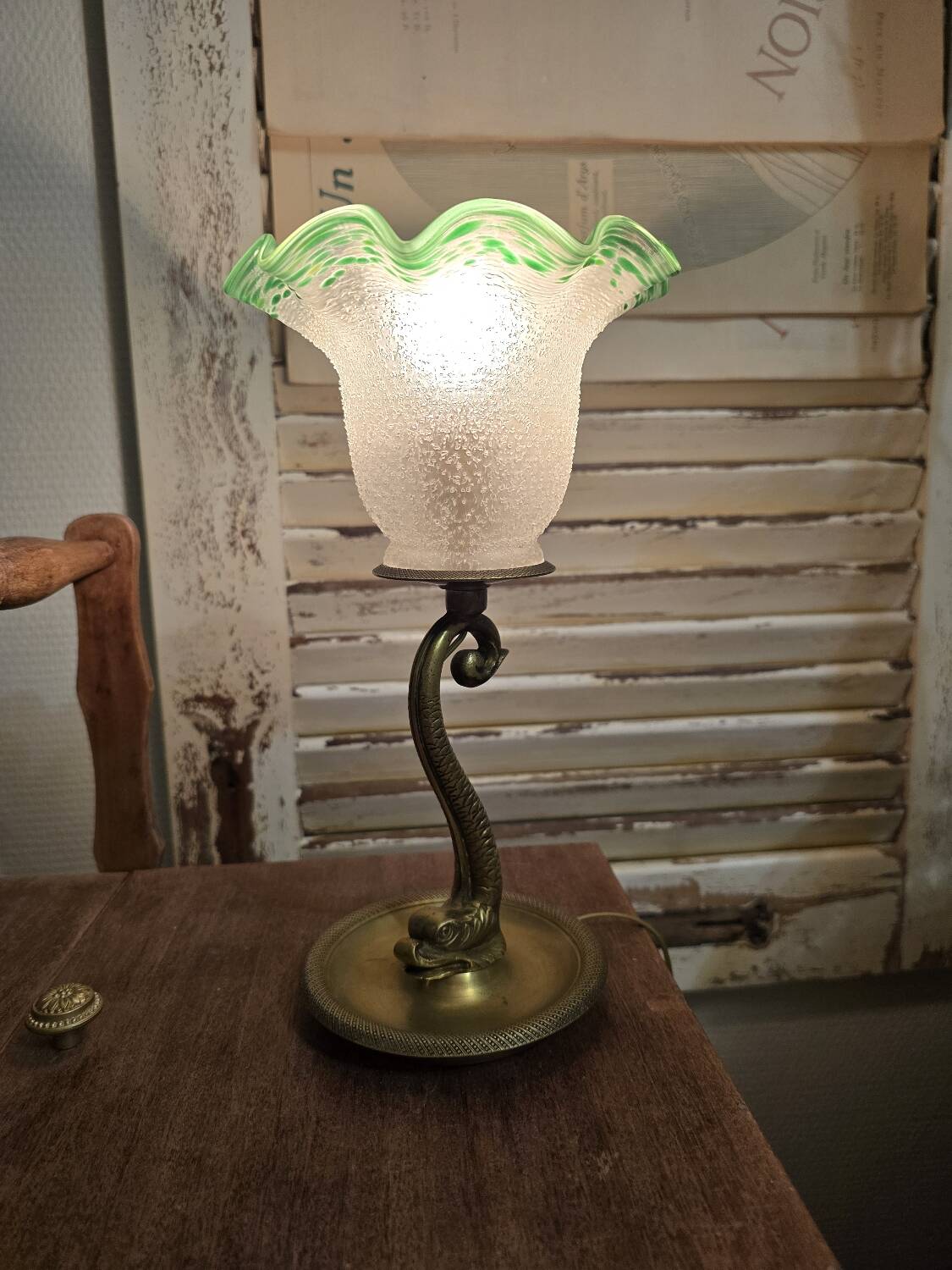 Small table lamp with a brass fish base and a tulip shade with green edges.