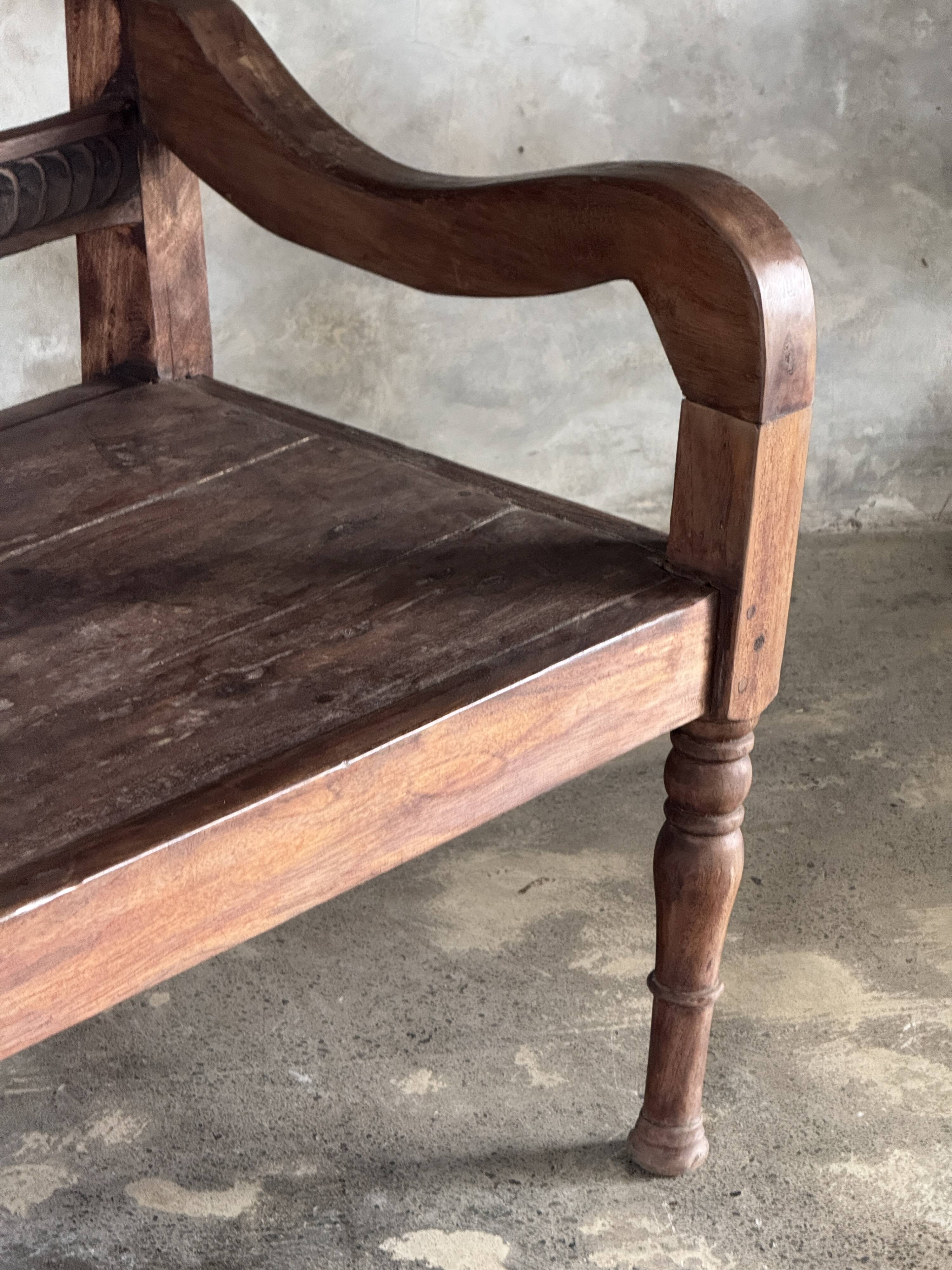 Small antique Indonesian bench in carved teak with plant and floral motifs.