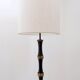 Tripod floor lamp in wrought iron and brass with bamboo-style base.