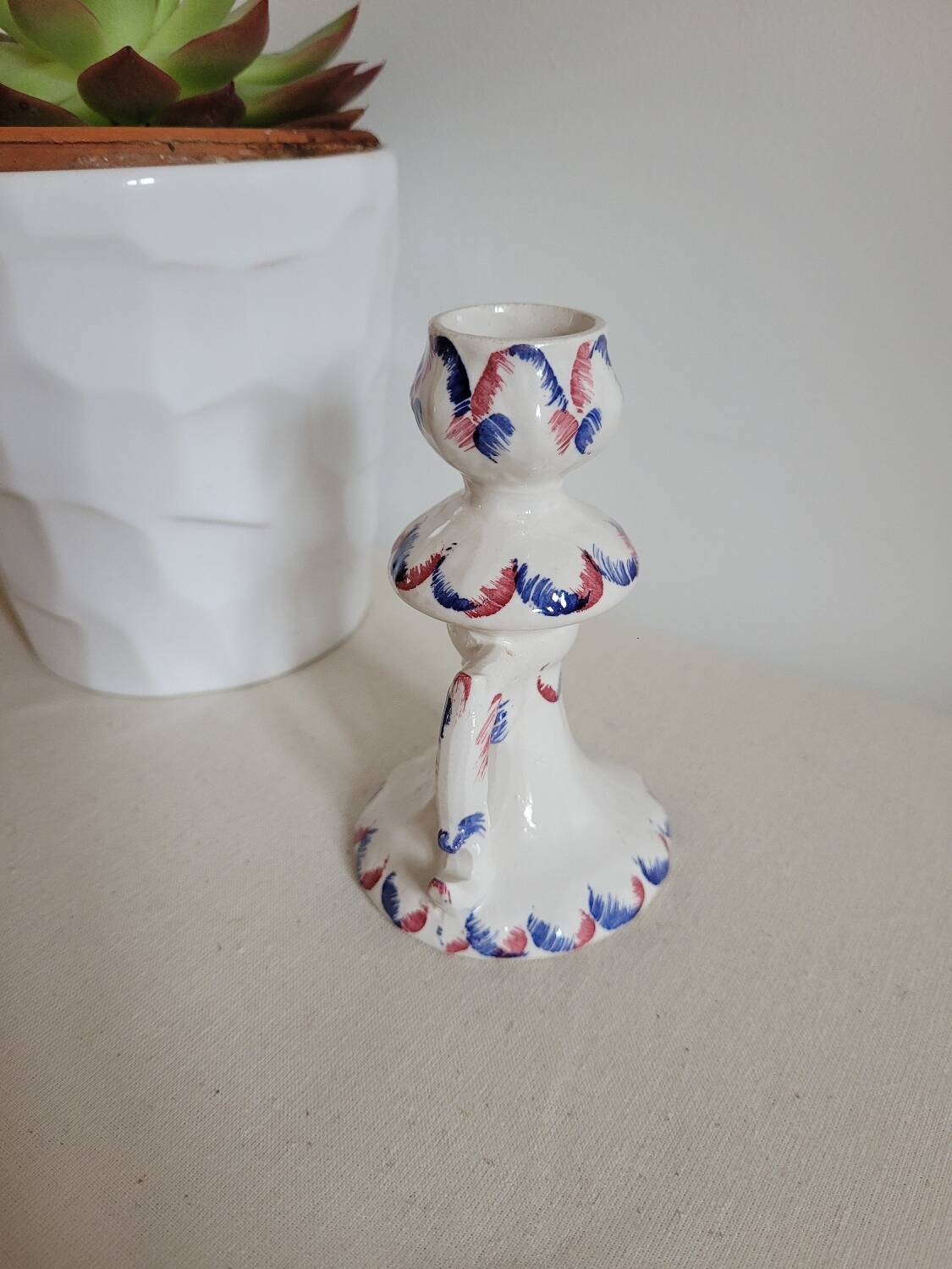 Ceramic candlestick with red and blue decoration.