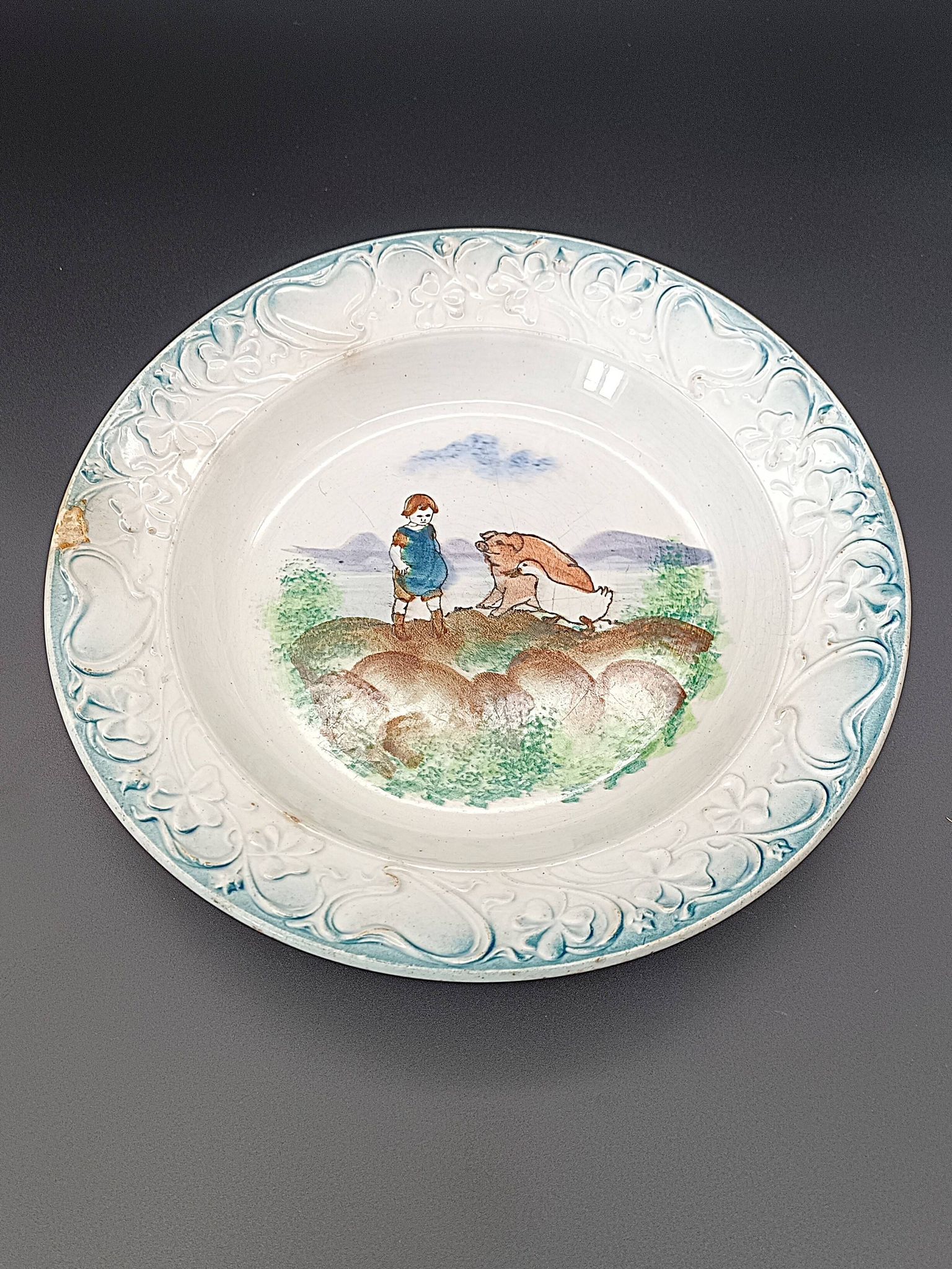 Large antique hollow dish from the 19th century, earthenware with pastoral decoration featuring a child, pig, and goose.