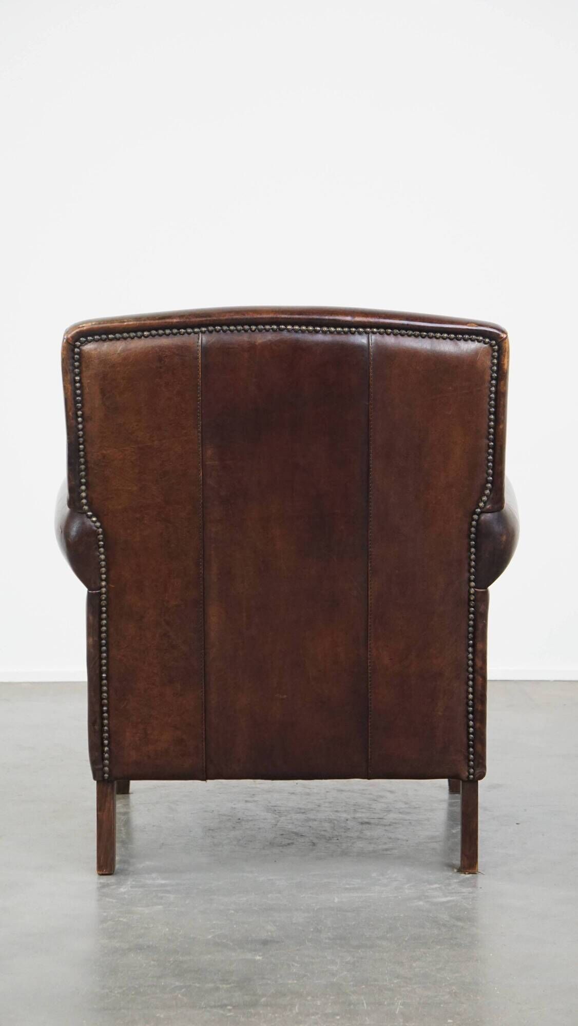 Dark brown sheepskin armchair finished with decorative nails