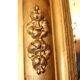 Miroir rectangulaire en bois doré à décor en relief de fleurs.