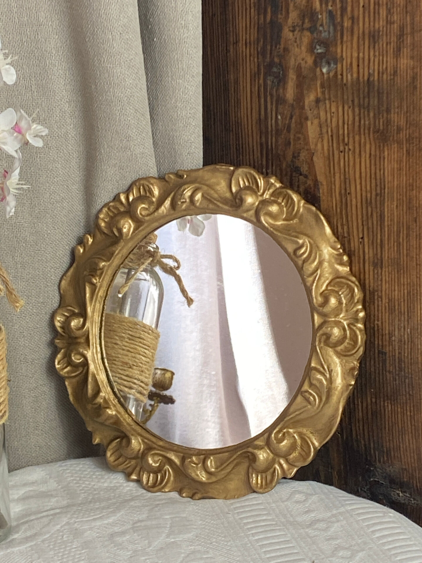 Round wooden mirror in golden colour.