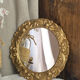 Round wooden mirror in golden colour.