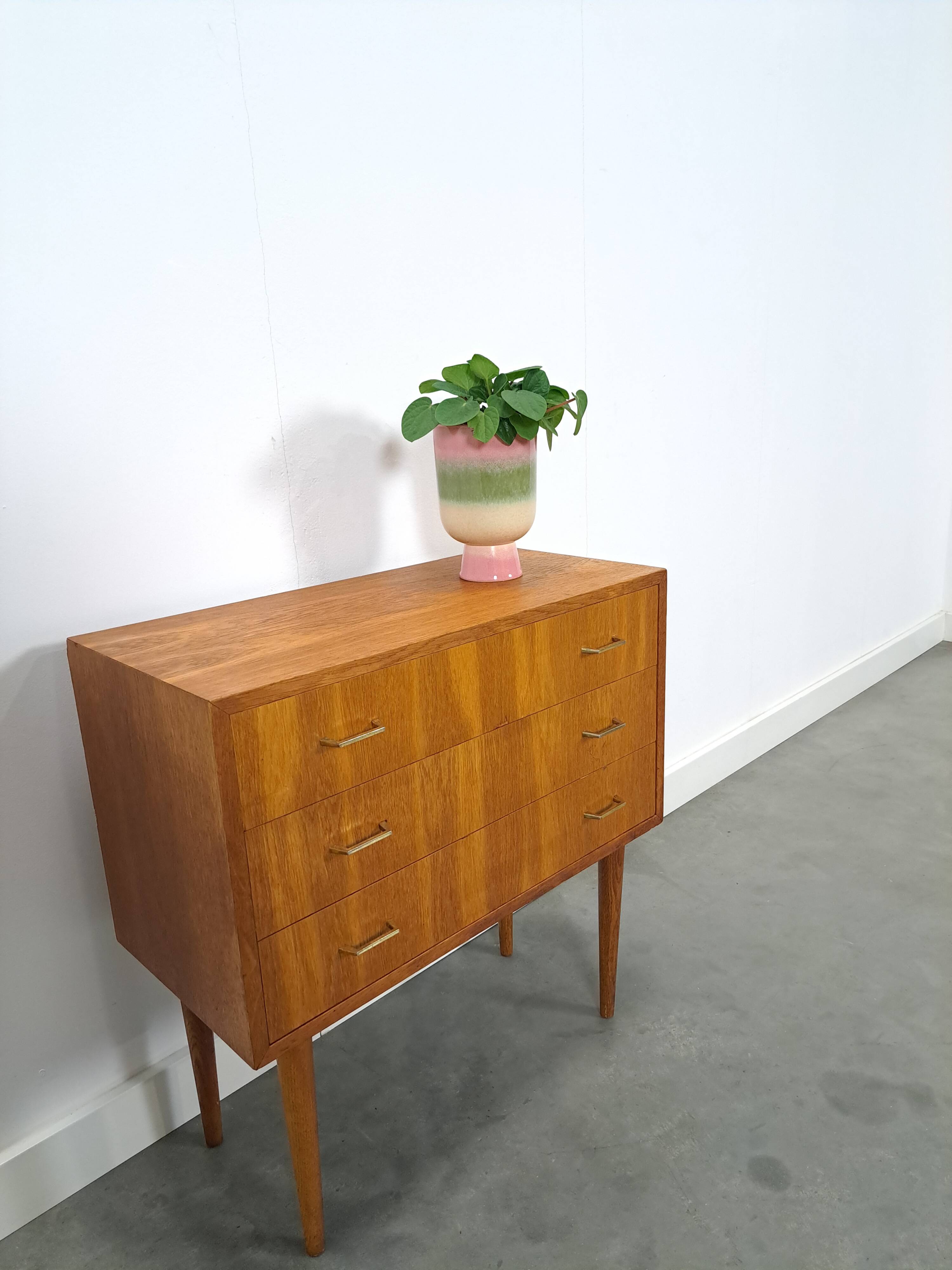 Commode danoise avec de hauts pieds et des poignées dorées.