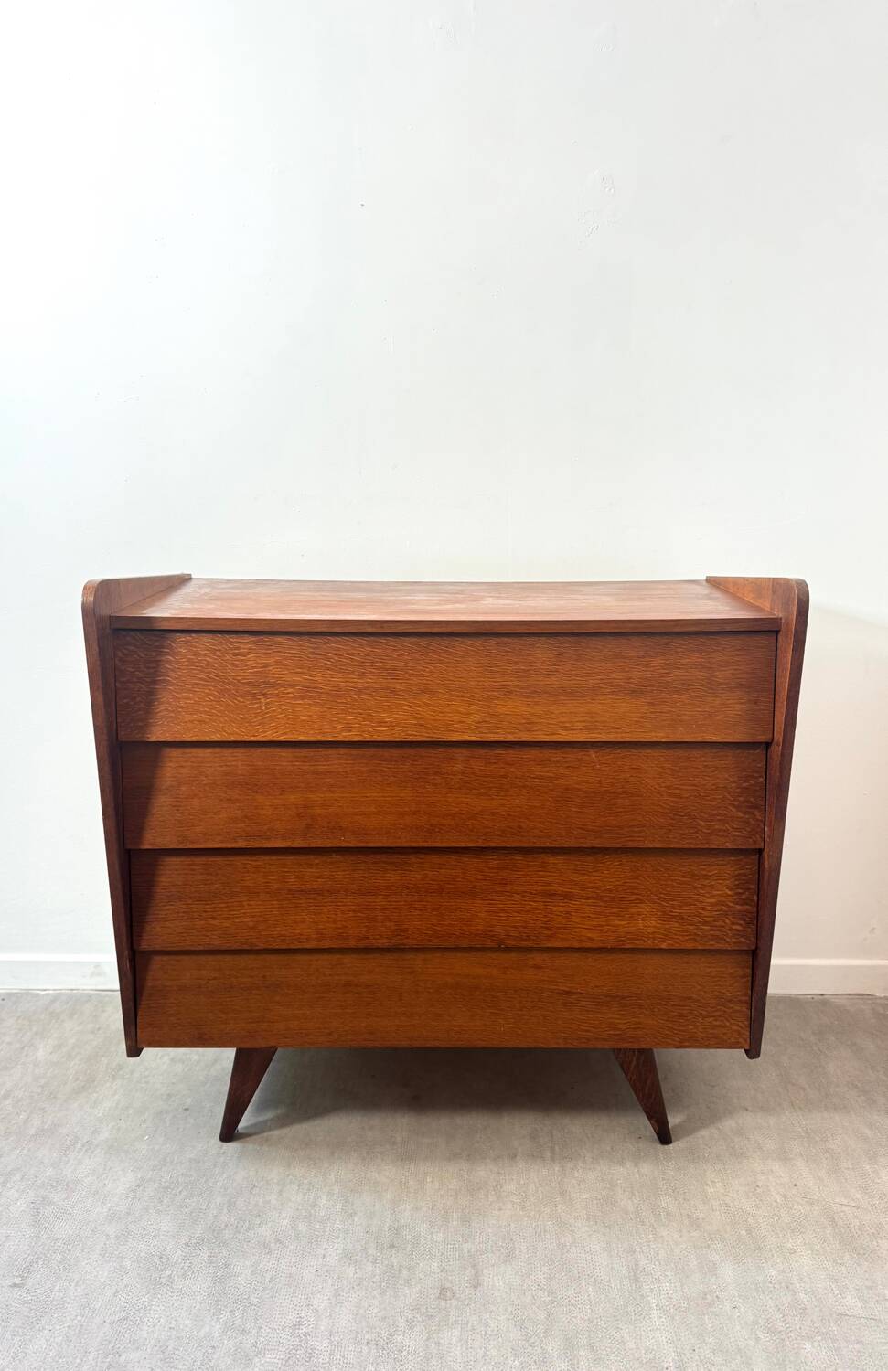 Vintage wooden chest of drawers with tapered legs.