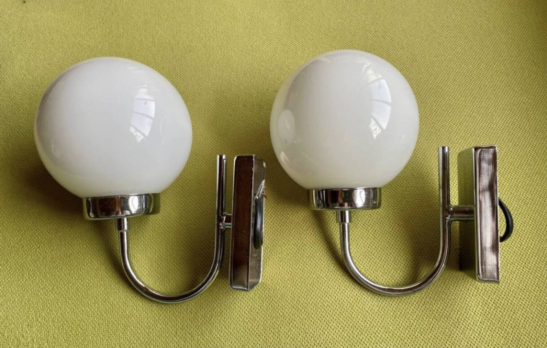 Pair of chrome metal wall lights with white glass globe.