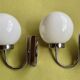 Pair of chrome metal wall lights with white glass globe.