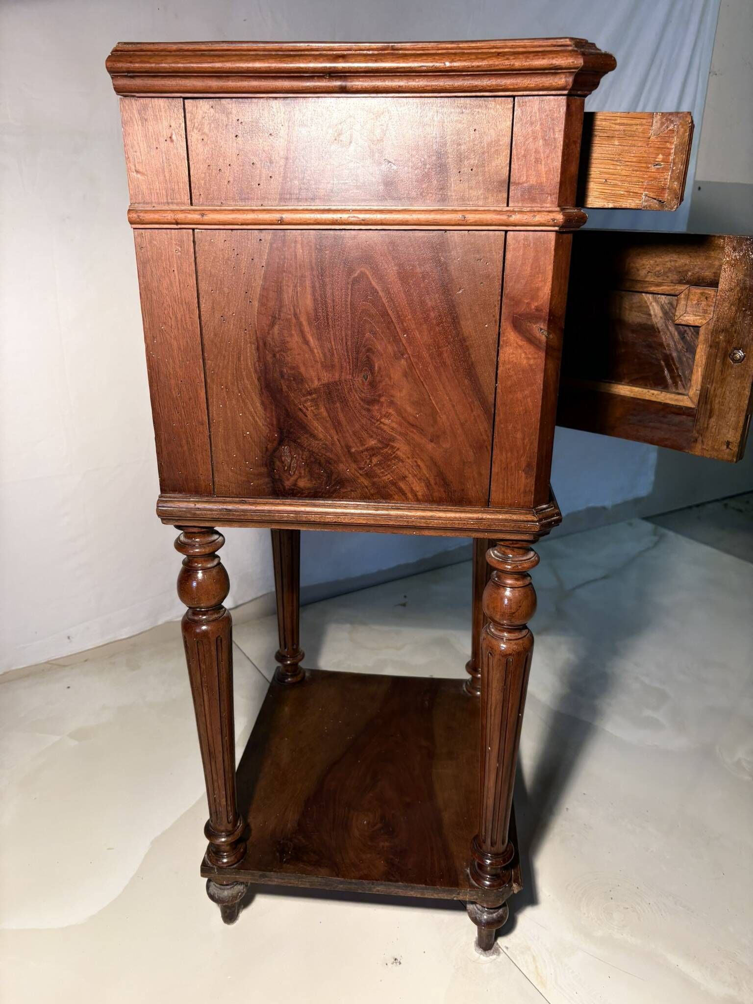 Antique wooden bedside table with turned legs.